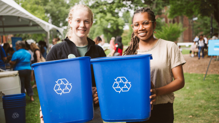 两个学生，每人拿着一个蓝色的回收箱